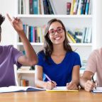 Happy students studying together at a table, representing engagement in the HND in Healthcare Management program.