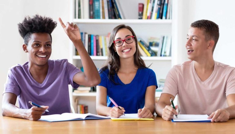 Happy students studying together at a table, representing engagement in the HND in Healthcare Management program.