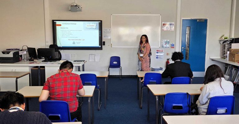 Classroom session with students writing as instructor leads the Empowering Future Talent: MRC Delivers CV & Cover Letter Workshop at Chadwell Heath Academy.