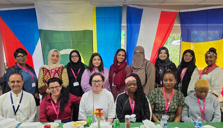 Group of staff and students posing with international flags in the background during Mont Rose College’s Multicultural Day.