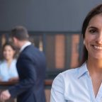 Smiling hospitality professional in uniform with colleagues in background, representing HND in Hospitality Management career opportunities.