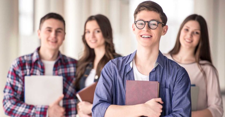 Smiling students holding books, representing Empowering Students Digital Skills in an academic setting.