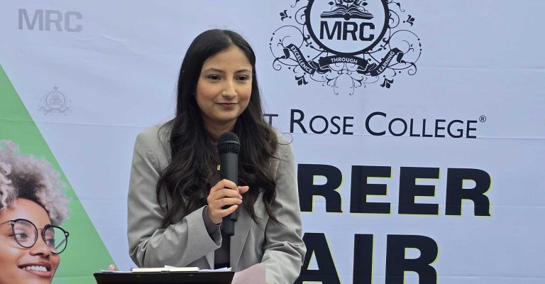 Woman speaking into a microphone at Mont Rose College Careers Fair 2025, standing in front of event banner.
