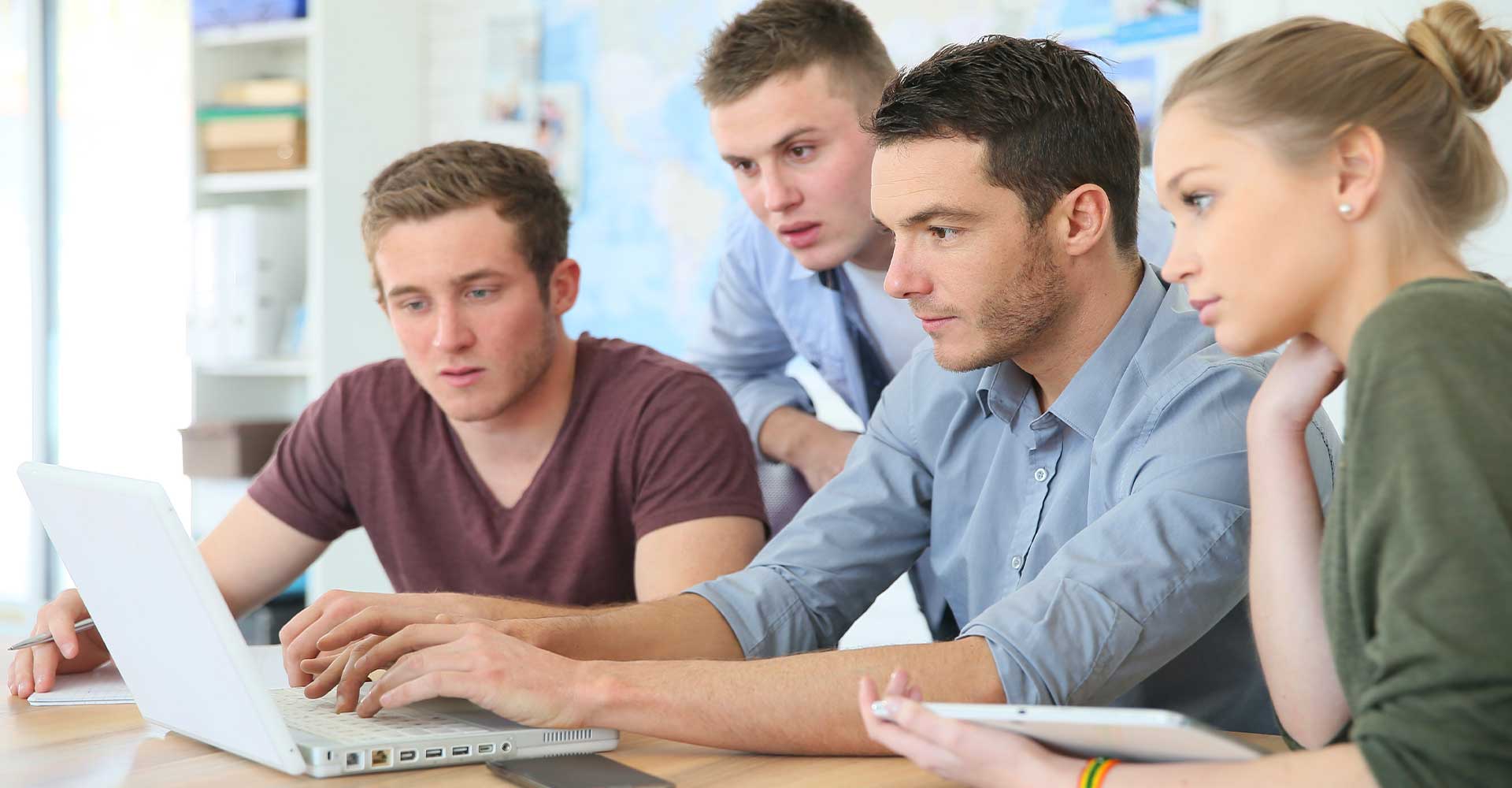 Focused students working together on a laptop, representing HND language requirements for international students.