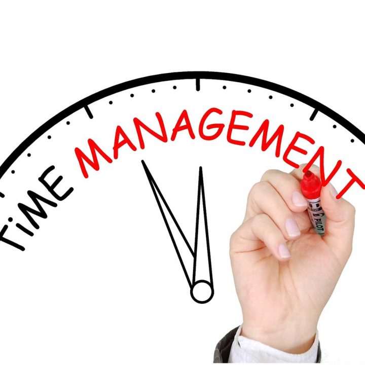 Hand writing “Time Management” on a clock graphic, symbolizing the concept of effective time management.