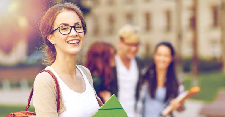 Smiling mature student on campus holding folder, representing mature student HND admission requirements.