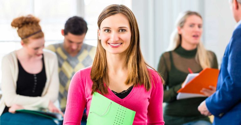 Smiling student holding folder in classroom setting, representing HND entry requirements for higher education.