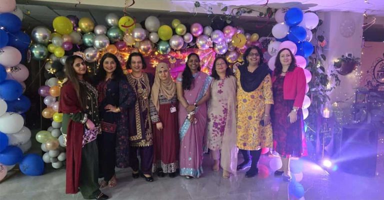 Female staff dressed in traditional attire posing with festive decorations and balloons as Mont Rose College celebrates Diwali.