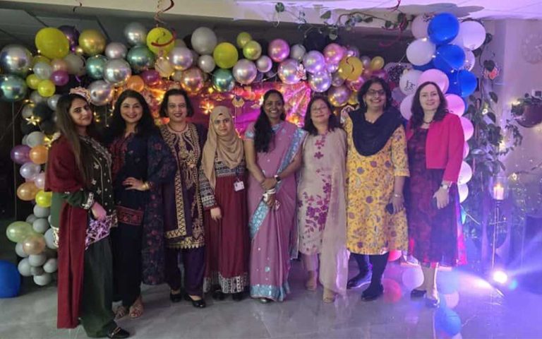 Female staff dressed in traditional attire posing with festive decorations and balloons as Mont Rose College celebrates Diwali.