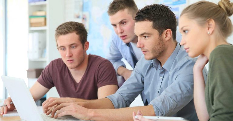 Group of focused students working together on a laptop, representing HND entry requirements for part-time students.